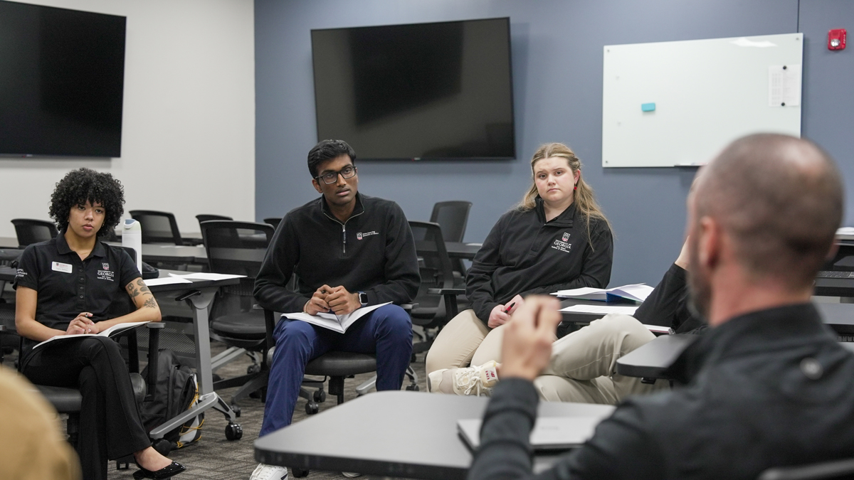 From left to right: Taylor Siefken, Yash Sajjan and Macy Hall listen as Emanuel County officials speak about the county’s storm response at a community meeting. (Photo by Sara Ingram)