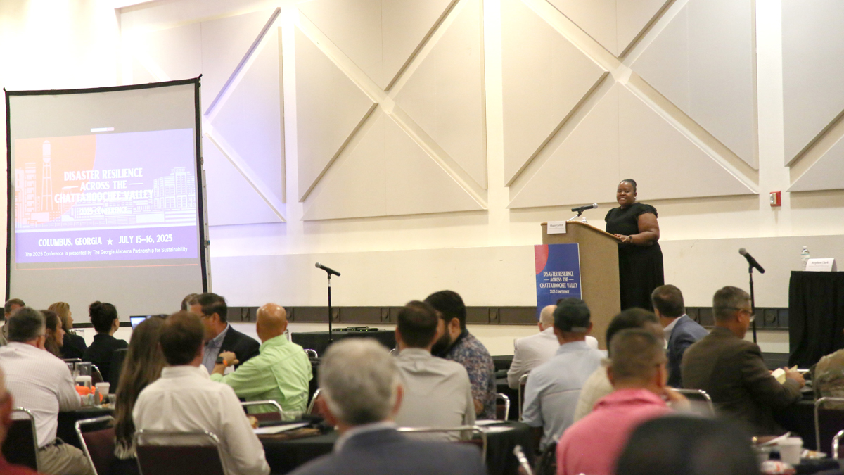 People sitting in a room listening to a speaker give a presentation.
