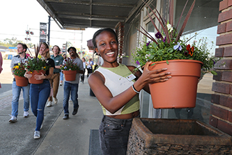 Linet Namuli, a third-year economics major from Kampala, Uganda, helps place planters in downtown Baxley as part of the PROPEL Rural Scholars program. 