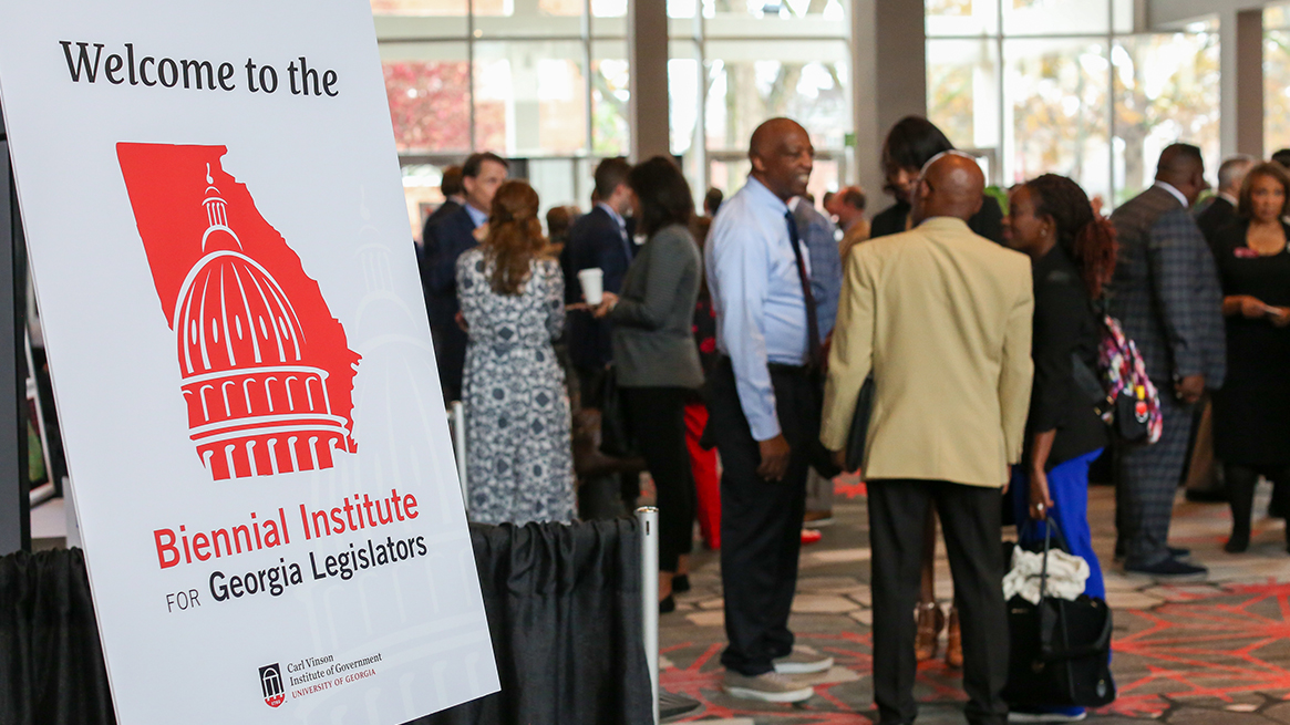Welcome sign at entry for the Biennial Institute for Georgia Legislators. People network in the background.